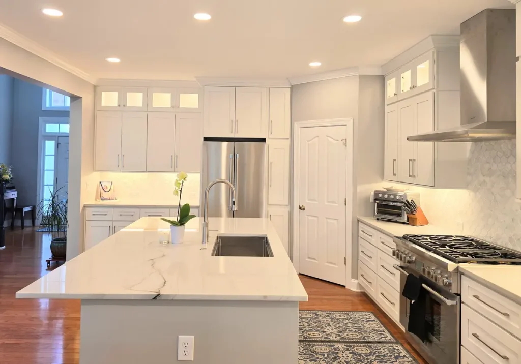 7 Day Kitchens remodel in Charlotte NC with white cabinets, stainless appliances, marble island, wood floors, and recessed lighting.