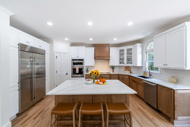 Modern kitchen by 7 Day Kitchens with white and wood cabinets, stainless appliances, marble island, and flowers—ideal for remodels.